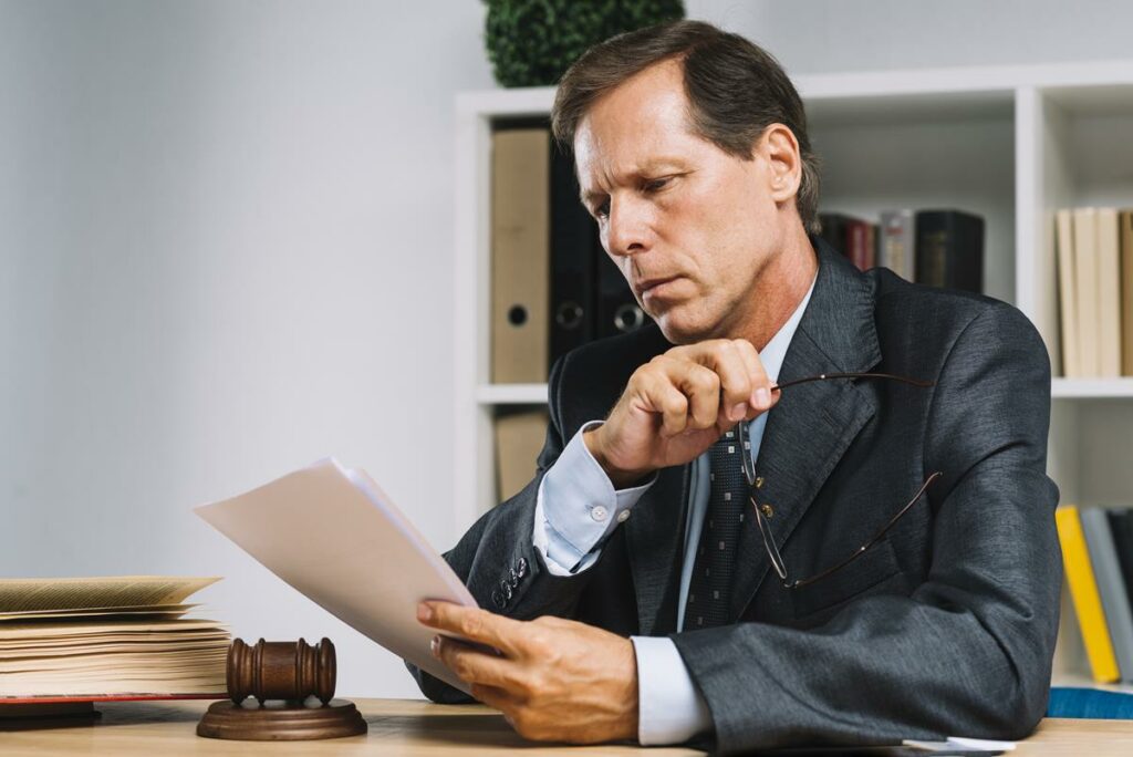 foto de um advogado na mesa de trabalho lendo papeis. 