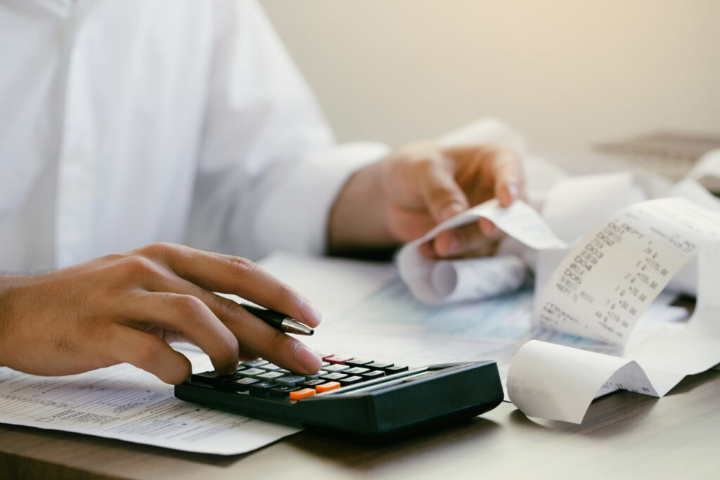 foto de uma mão de um homem com uma calculadora, fazendo contas